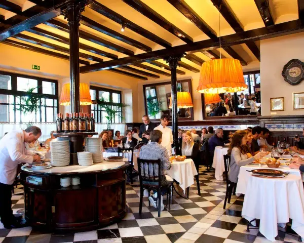 Un camarero prepara platos en un restaurante lleno de comensales. Los pasos para abrir un restaurante incluyen crear un ambiente acogedor como este.