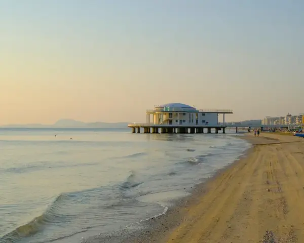Alba dorata sul mare di Senigallia, con il celebre edificio sul mare e la spiaggia che si estende verso la città.