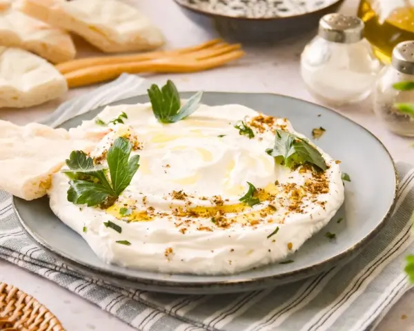 Labneh cremoso con aceite de oliva, za'atar y perejil, servido con pan de pita.