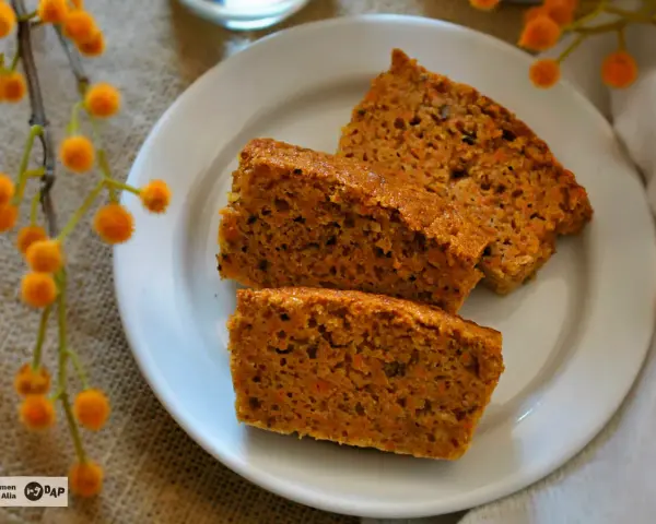 Rebanadas de bizcocho de zanahoria casero, esponjoso y con trocitos de zanahoria visibles, servidas en un plato blanco.