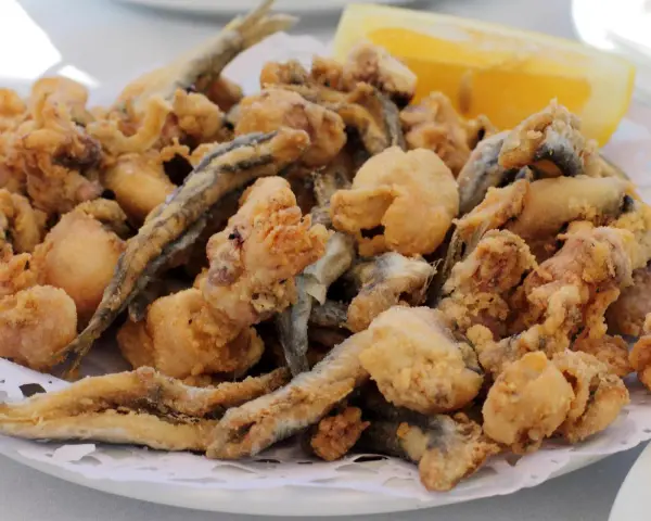 Frito y crujiente pescado en adobo, con trocitos de calamar y una rodaja de limón.