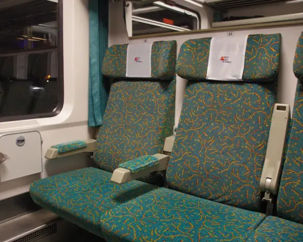 Wnętrze wagonu 4 Pendolino. Widok na dwa rzędy siedzeń z charakterystycznym wzorem.