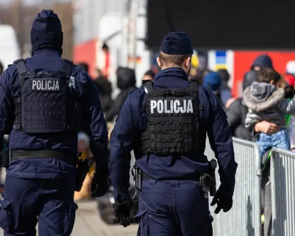 Dwóch policjantów w kamizelkach taktycznych pilnuje porządku. Chcesz wiedzieć, co trzeba zrobić, żeby zostać policjantem?