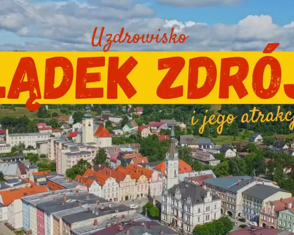 Widok na Lądek Zdrój i jego atrakcje. Miasto z kolorowymi kamienicami, kościołem i zielonymi wzgórzami w tle.