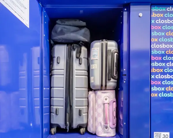 Luggage stored in a blue locker, including suitcases and bags.