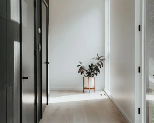 Ideas para como decorar un recibidor pequeño: una planta en maceta blanca sobre un soporte de madera ilumina el pasillo.