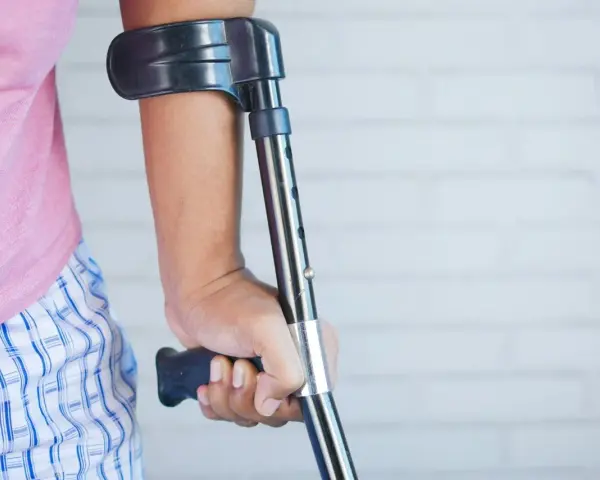 Osoba z kulą, być może po wypadku, który mógłby być opisany jako art. 156 kk. Różowa koszulka i kratkowane spodenki.