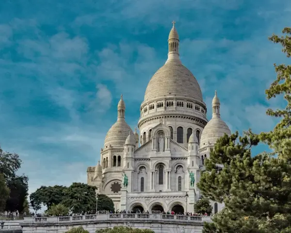 Basílica del Sacré-Cœur, uno de los monumentos de Francia, se alza majestuosa bajo un cielo azul con nubes.