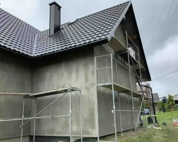 Dom w trakcie ocieplania, rusztowania wokół ścian. Zastanawiasz się, ile kosztuje ocieplenie domu?