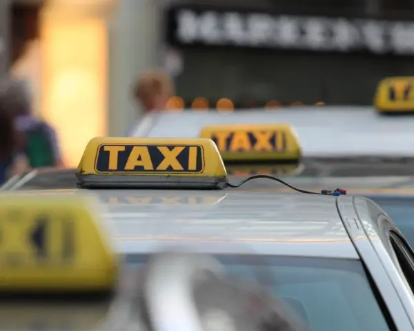 Reihe von Taxis mit gelben Dachschildern. Die aktuellen Taxipreise sind auf den Schildern nicht sichtbar, aber die Fahrzeuge stehen bereit.