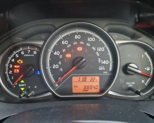 Kontrolka silnika świeci się na desce rozdzielczej Toyoty, wskazując błąd DTC P1604. Odometer pokazuje 88940 mil.