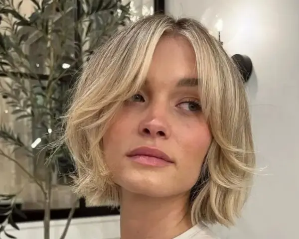 Kobieta z blond włosami w stylu cienkie włosy bob warstwowy cieniowany, z delikatnymi falami i grzywką na bok.