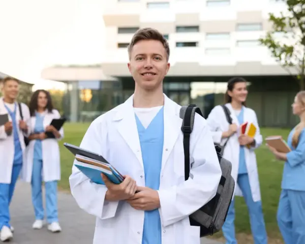 Uśmiechnięty student medycyny z książkami, gotowy na wyzwania studiów psychologicznych. Wymagania są wysokie, ale cel jest jasny.