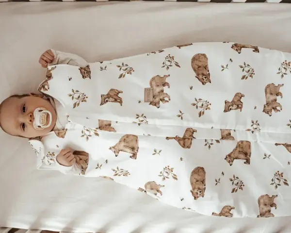 Niemowlę w śpiworku z misiami i pszczołami. Od kiedy kołderka dla niemowlaka jest tak urocza, sen staje się przyjemnością.