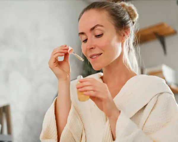 Frau mit einem Tropfen Serum in der Pipette, bereit für ihre Hautpflege-Routine. Ob Retinol oder Hyaluron, sie wählt das Beste für ihre Haut.