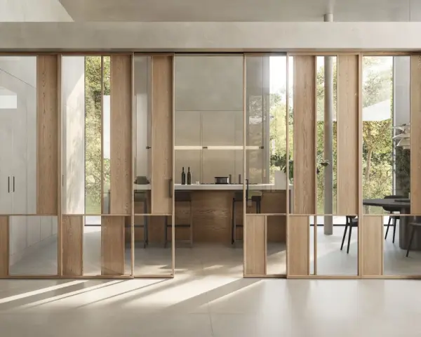Porta scorrevole in legno e vetro, con riflessi che creano un effetto di profondità. Un esempio di **brutalismo interni** con un tocco di leggerezza.