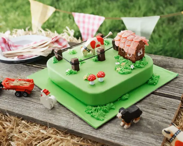 Torta per bambini a tema fattoria con mucca, casetta, trattore e animali.