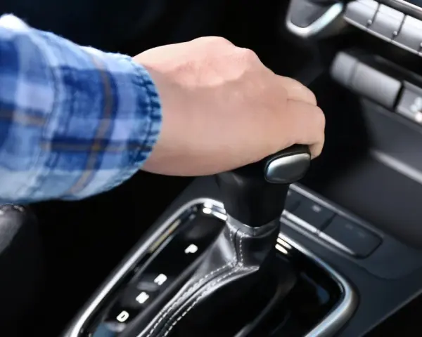 Dłoń na dźwigni zmiany biegów w aucie z funkcją auto hold i manualną skrzynią.