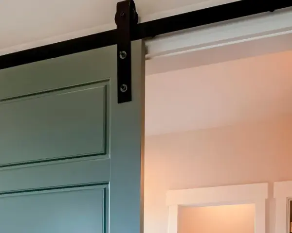 Trasformare porta battente in scorrevole: una porta verde acqua con binario nero, un'elegante soluzione moderna per ottimizzare gli spazi.