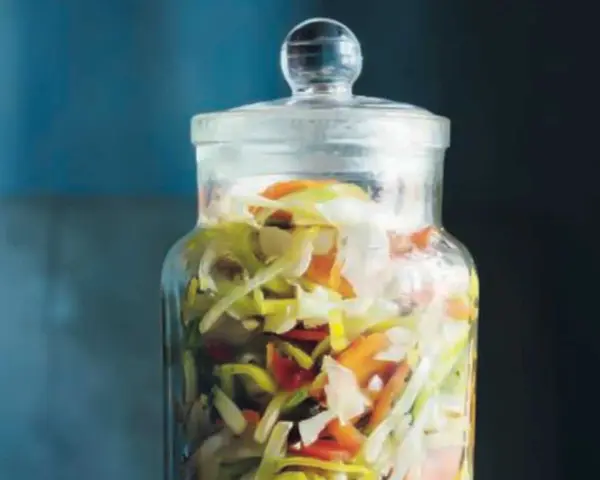 En glasburk fylld med strimlad vitkål, morötter och purjolök, redo för en 3 veckors sallad.