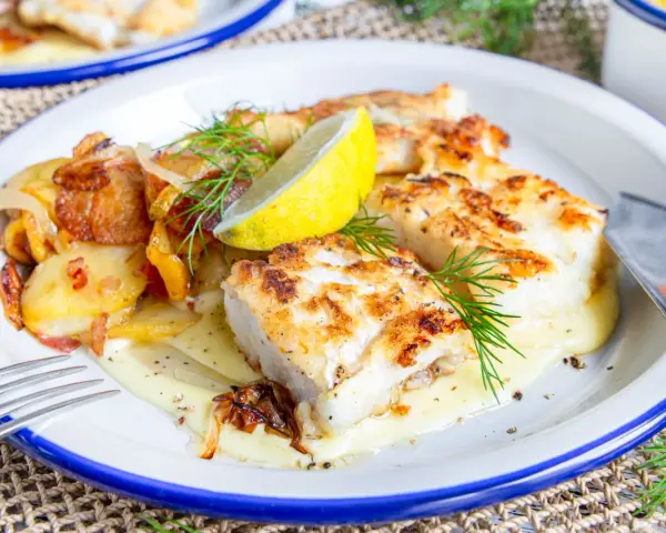 Gebratener Fisch mit Bratkartoffeln und Zwiebeln, garniert mit Dill und Zitrone. So sieht leckerer Pannfisch aus!