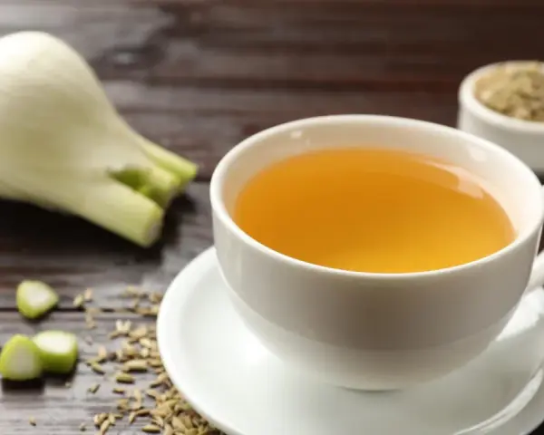 Una taza de infusión de hinojo por la noche, con hinojo fresco y semillas esparcidas.