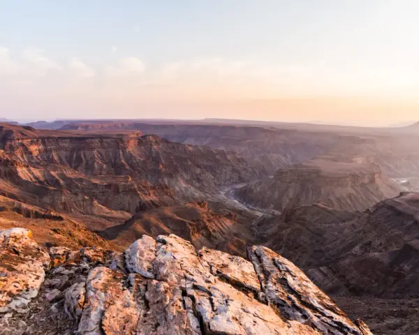 Wąwóz Fish River w Namibii, z rzeką wijącą się w dole. Zachodzące słońce maluje skały na ciepłe barwy.