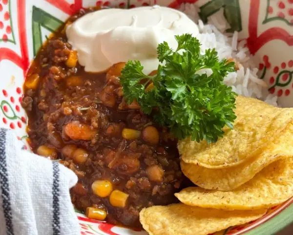 En skål med chili con carne, ris, gräddfil och tortillachips. Perfekt vin till chili con carne!
