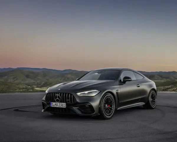 Mroczny Mercedes CLE 53 AMG na tle górskiego krajobrazu o zachodzie słońca.