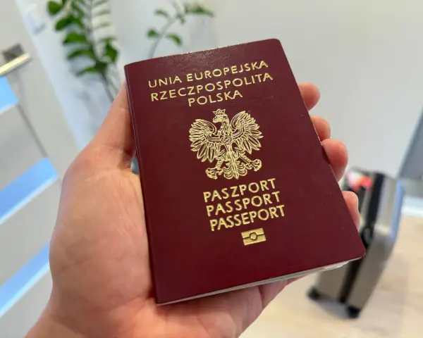 Polski paszport w dłoni. Czy do USA potrzebna jest wiza? Podróż w toku, walizka czeka.