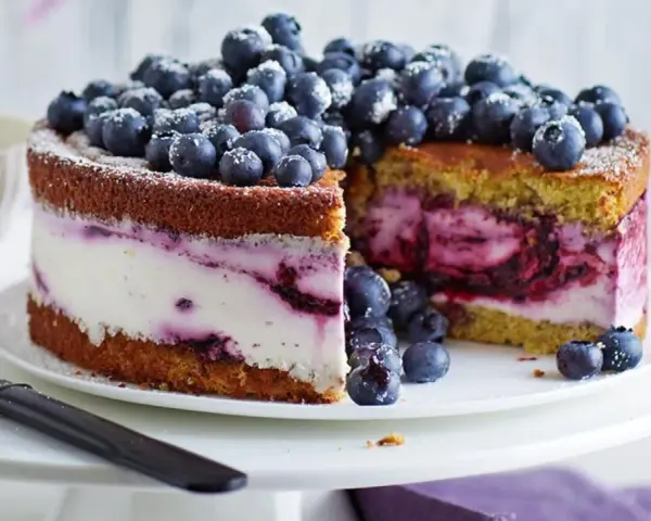 Saftige Heidelbeertorte mit Joghurt-Füllung, garniert mit frischen Beeren und Puderzucker. Ein Genuss für Augen und Gaumen.