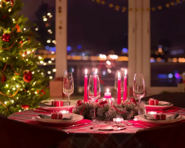 Ett dukat bord med julgran och tända ljus, redo för ett härligt vin till julbordet.