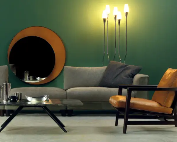 Elegante soggiorno con divano grigio, poltrona in pelle color cuoio e specchio rotondo. Idee su come abbinare divano e poltrone diverse.