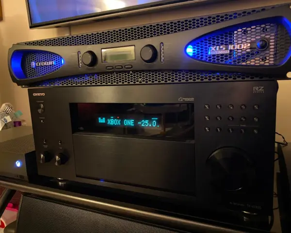 Wzmacniacz Crown XLS 1002 z niebieskim podświetleniem, umieszczony nad amplitunerem Onkyo.