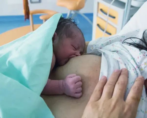 Neugeborenes Baby an der Brust der Mutter, ein Moment der stillen Geburt und des ersten Kontakts.