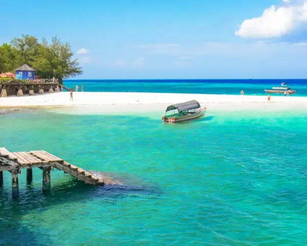 Zanzibar - wczasy opinie: turkusowa woda, biała plaża, drewniany pomost i łodzie. Rajskie widoki idealne na wakacje.