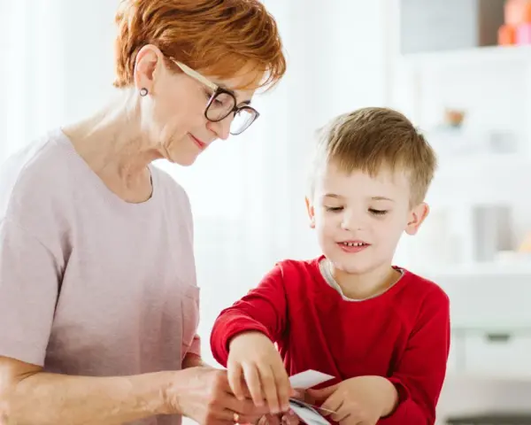 Babcia pomaga wnuczkowi w zajęciach, które mogą być częścią terapii stereotypii ruchowych.
