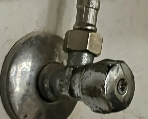 Metalowy zawór wodny, pokazujący, jak odkrecic zawor z woda. Widoczny śrubunek i pokrętło.