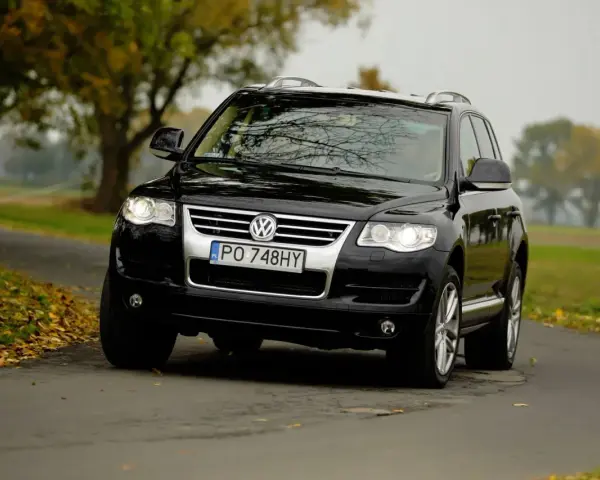 Czarny VW Touareg 2.5 TDI R5 na jesiennej drodze. Choć to solidne auto, warto znać jego potencjalne wady.