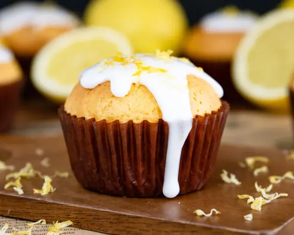 Zitronenmuffins mit weißer Glasur und Zitronenschale, die an eine Backmischung für Zitronenmuffins erinnern.
