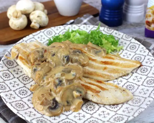 Sabroso pollo con champiñones en salsa cremosa, servido con lechuga fresca en un plato decorado.
