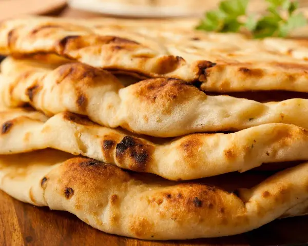 Gestapeltes, frisch gebackenes Naan Brot mit leichten Röststellen. Perfekt zum Dippen!