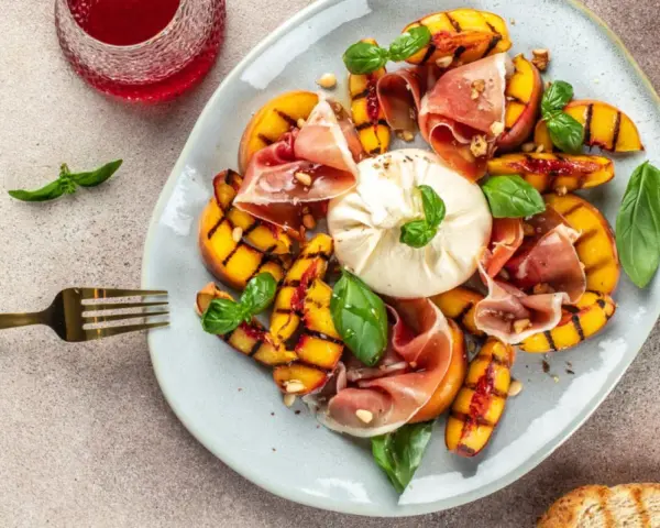 Gegrillte Pfirsiche mit cremigem Burrata, Prosciutto und Basilikum – ein köstlicher Pfirsich Burrata Genuss.