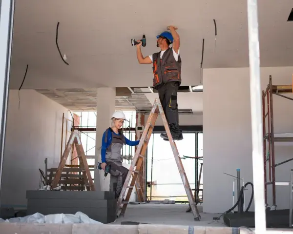 Dwóch budowlańców na drabinach montuje instalację elektryczną. Czy jest ulga na remont mieszkania?