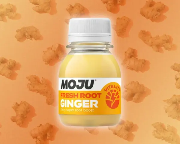 Botella de MOJU con shots de jengibre fresco, rodeada de raíces de jengibre. Un impulso de vitalidad.