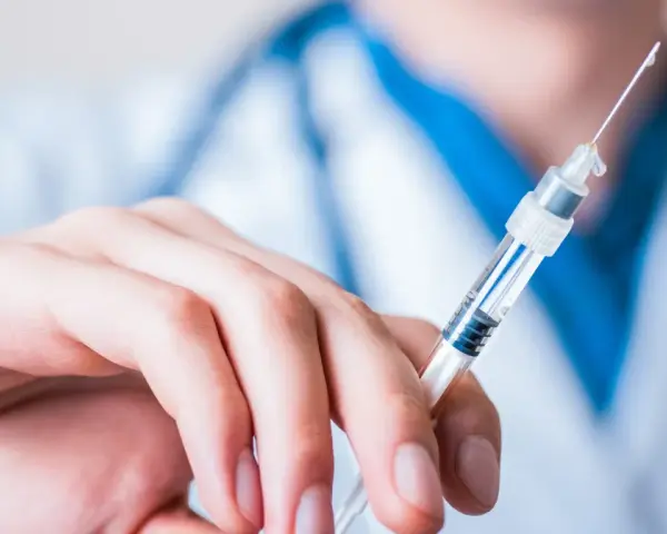 Dłoń trzymająca strzykawkę z heparyną. Pytanie: gdzie wyrzucić strzykawki po heparynie? Bezpieczne utylizowanie jest kluczowe.