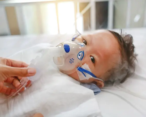 Dziecko z maską tlenową, być może z powodu RSV. Co to jest RSV? To wirus, który może być groźny dla najmłodszych.
