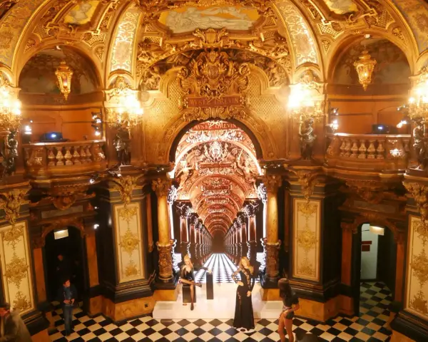 L'intérieur doré et orné du musée Grévin à Paris, avec des statues de cire et un sol à damier.