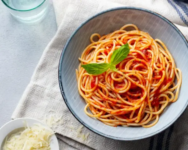 Misternie ułożone spaghetti z sosem pomidorowym i listkiem bazylii. Idealne jakie przyprawy do spaghetti? Sól, pieprz i odrobina czosnku.
