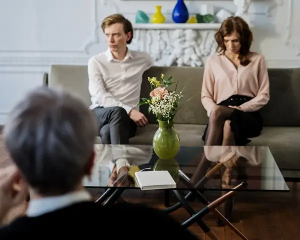 Un couple en discussion avec un avocat, cherchant une aide juridictionnelle pour leur divorce.